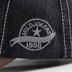 Macro view of white embroidery and stars on premium black denim fabric on baseball cap
