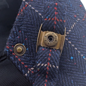 Close-up of navy tweed herringbone fabric with star-patterned bronze metal buckle detail