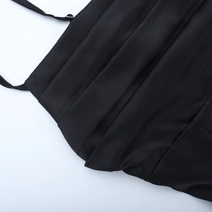 Detail view of black satin dress featuring delicate thin straps and pleated fabric texture