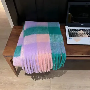 Macro detail of colorful oversized plaid scarf with tassels on a wooden background