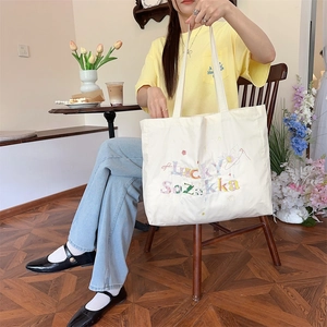 Détail de la broderie en relief colorée et du texte Lucky Sozakka sur le sac cabas en toile