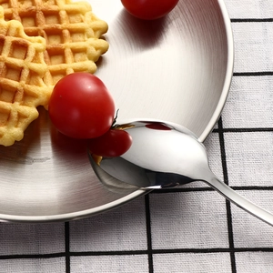 Outdoor stainless steel camping cutlery set with spoon and plate on checkered tablecloth