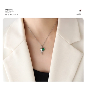 Detailed close-up of molten heart pendant necklace with green zircon on white blazer