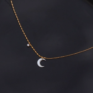 Detail shot of golden crescent moon pendant with round crystal on a delicate chain