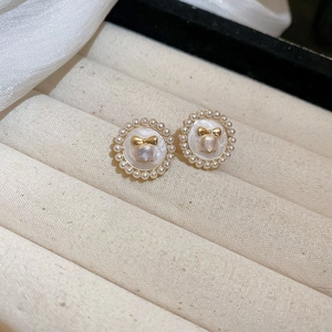 Vue macro de boucles d'oreilles vintage avec petites perles et un nœud doré chic