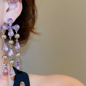Detailed close-up of purple teardrop crystal fringe earrings with silver beads worn by a model