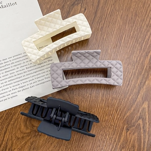 Quilted pattern large claw hair clips in cream, grey, and black on a wooden table