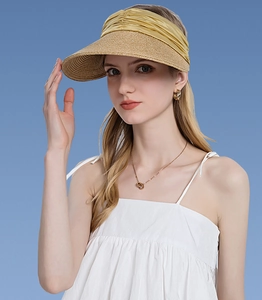 Detail of woven straw sun visor with golden satin ribbon wrap against a blue background