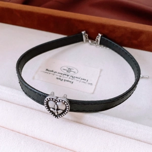 Detail of vintage heart pendant with cross relief on black leather adjustable choker necklace