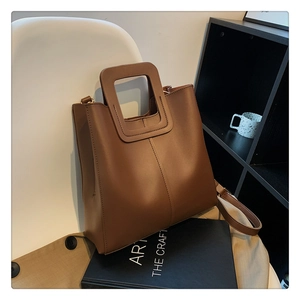 Brown retro tote bag with hollow handles placed on a white chair for daily style