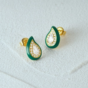 Close-up of golden teardrop stud earrings with green enamel and clear zircon stones