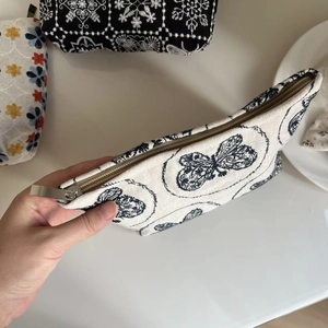 Detail view of butterfly pattern canvas pouch featuring a smooth metal zipper closure