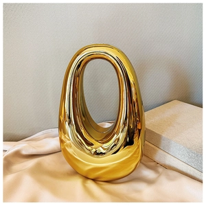 Close-up of golden oval acrylic evening bag with a sleek streamlined design on silk fabric