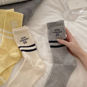 Three pairs of striped cotton crew socks with athletic embroidery on white fabric