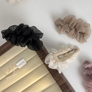 Close-up of four soft mesh fabric hairpins in black, cream, khaki, and purple colors