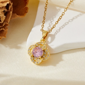 Vue détaillée du pendentif fleur dorée avec pierres roses sur un tissu en soie beige