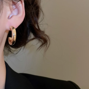 Close-up of minimalist gold-plated wide C-shape hoop earring worn by a female model