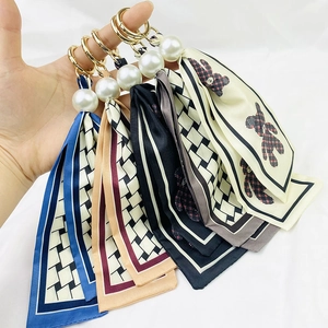 Detail of colorful silk scarf keychains with gold rings, pearls, and bear patterns