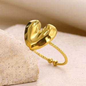 Macro detail of golden bubble heart ring with twisted rope band on a stone base