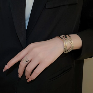Detail of hollow geometric metal bracelet and ring set on model in gold finish