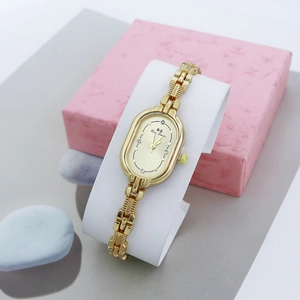Détails du cadran de montre ovale doré avec un fin bracelet à maillons métalliques