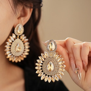 Close-up of oversized vintage gold teardrop earrings with sparkling champagne crystals