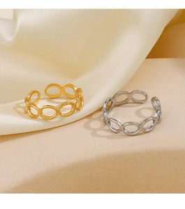 Close-up of gold and silver hollow oval rings on a warm beige textured stone display