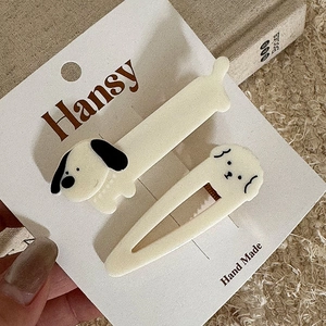 Close-up of handmade cream dog hair clips set on card with warm fabric background