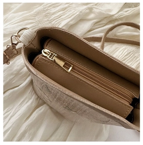Vue détaillée de la fermeture éclair dorée d'un sac seau rétro de couleur beige clair