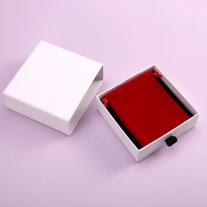 Detail of a white drawer jewelry box with a red velvet drawstring pouch gift packaging