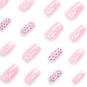 Glossy pink press-on nails with white leaf art and colorful rhinestones in 16-piece set
