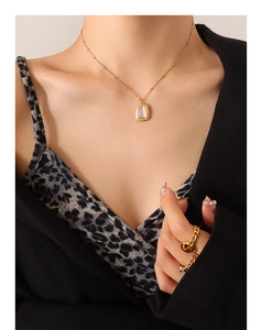 Close-up of a gold necklace with white stone pendant and matching rings on a woman