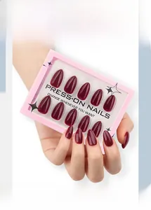 Detail of glossy wine red press-on nails in oval shape with clear display packaging
