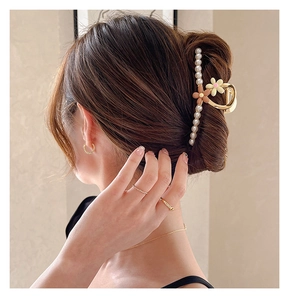 Gros plan d'une pince à cheveux dorée avec perles et fleurs sur les cheveux