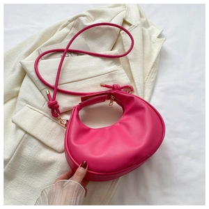 Detail of a pink crescent-shaped leather handbag featuring unique knotted strap design