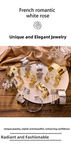 Detail view of golden butterfly and flower open bracelets on white plate with silk