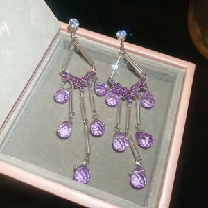 Macro view of silver tassel earrings with purple crystals in a pink velvet jewelry box