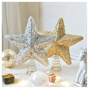 Detail of glittery champagne gold and silver star tree topper with metal spring base