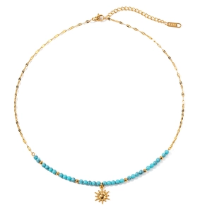 Collier en acier titane doré avec perles turquoise et pendentif soleil sur fond blanc