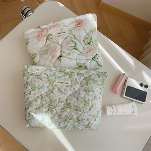 Detailed texture of pink rose and green floral quilted cotton makeup bags on a desk