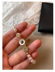 Détail de bracelet en perles plaqué or 18k avec breloques en zircon bleu et blanc