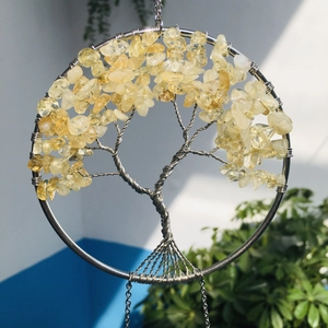 Close-up of handmade tree of life ornament with yellow crystals and silver wire wrap