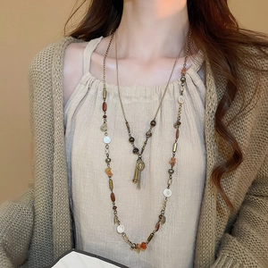 Dettaglio di collana vintage boho a strati con frange in metallo e perline miste