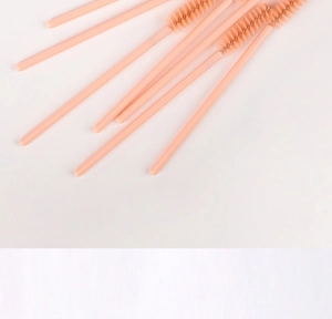 Close-up of disposable pink eyelash wands with spiral fiber heads in a neat row