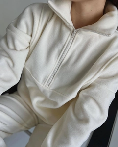 Détail d'un sweat en polaire crème montrant le col zippé et la texture douce du tissu