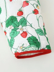 Detail shot of strawberry print quilted cotton fabric with red piping and fine stitching