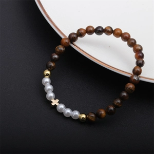 Détail du bracelet en perles œil de tigre avec perles blanches et pendentif croix dorée