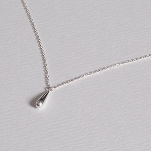Macro shot of minimalist 925 sterling silver water drop pendant on a fine chain