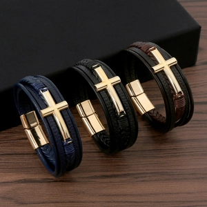 Men's woven leather bracelets with gold cross and magnetic clasp on wooden background