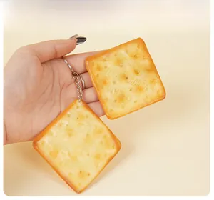 Dettaglio di un portachiavi a forma di cracker in PVC tenuto in mano per scala dimensionale